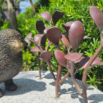 一株株銅葉舒展枝姿，在陽光下閃耀生命的光澤，鳥兒靜靜守望，為街道增添自然的詩意。