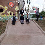 新業(yè)建設(shè)卓勝隆董事長(中)與來賓童心大發(fā)，一起玩溜滑梯。