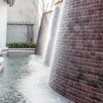 與接待大廳相對，僅隔一道玻璃落地窗即為「戶外水瀑牆」。流水潺潺與磚石沖刷出平整的紋路，水光相映下霧氣生騰，彷若仙境。－【新業(yè)觀峰】。