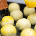 刷上蛋黃液，點(diǎn)上芝麻裝飾，圓潤蓬鬆的蛋黃酥即將穿上金黃酥脆的外衣。