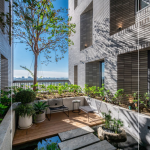 四季合院，每三層設(shè)計(jì)一處公共大露臺(tái)，從梯廳走入彷彿大家庭的合院(埕)，提供住戶們休憩及交誼空間，搭配四季主題的呼應(yīng)，此為七樓的夏季-種植小花紫薇與厚葉石斑木。