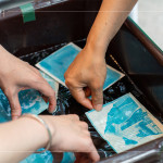 將明信片輕放入水箱中，清洗掉藥水後，隨著雙氧水的洗禮，藍(lán)曬圖像逐漸浮現(xiàn)。