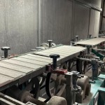 乾燥處理過的磁磚，整齊地陳列在輸送臺上，準(zhǔn)備進(jìn)入下一道逐層施釉的工序。